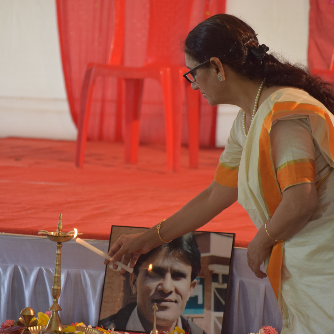 Triveni Acharya lighting an oil lamp beside a framed photograph of the late Balkrishna Acharya, who co-founded Rescue Foundation.
